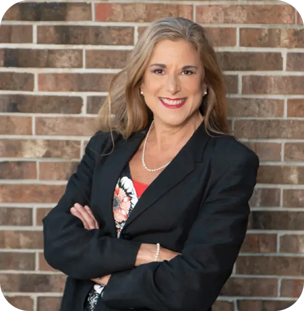 A woman standing in front of a brick wall.